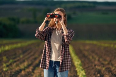 Dürbünden bakıyorum. Gündüz vakti güzel tarla tarlasında genç bir kadın var..