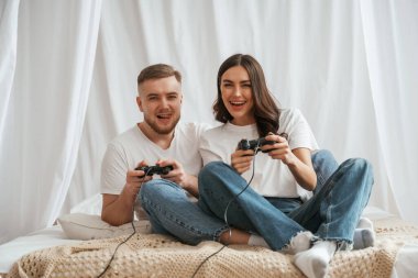 joysticklerle video oyunu oynuyorum. Genç çift evde birlikteler..