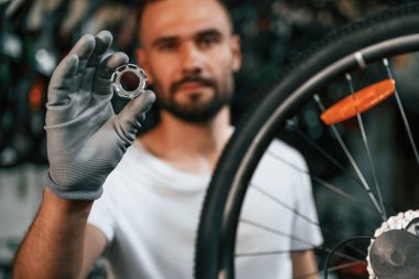 Direksiyonun yanında daire şeklinde parçalar var. Bisiklet dükkanında tamirci, mağazada çalışıyor..