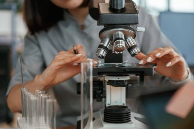 Mikroskopla. Paltolu kadın doktor içeride..