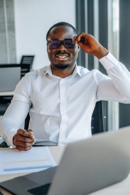 Dizüstü bilgisayarla. İşadamı modern ofiste çalışıyor..