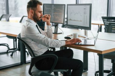 Laptop kullanıyorum. İşadamı bilgisayar başında oturuyor ve ofiste çalışıyor..