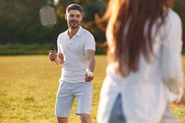 Yaz tarlasında. Kadın ve erkek badminton oynuyorlar..