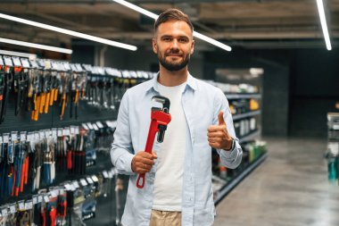 Kırmızı boru anahtarı. Adam hırdavatçıda..