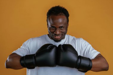 Eldivenli profesyonel boksör. Siyah adam sarı arka plana karşı..