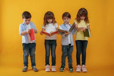 Ellerinde not defterleri, eğitim anlayışı. Çocuklar sarı arka plana karşı birlikte..