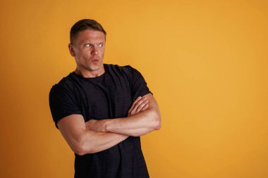 Kollarını kavuşturmuş duruyorsun. Adam stüdyoda arka plana karşı..