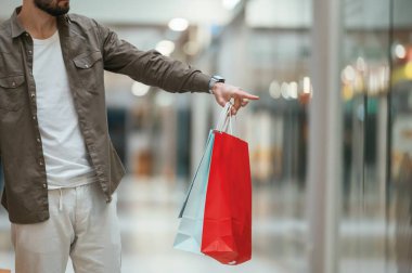 Manzara kapalı, alışveriş torbaları var. Adam süpermarkette alışveriş yapıyor..