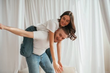 Adam kadını sırtında tutuyor, eğlenceli. Genç çift evde birlikteler..