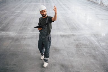 Önden bak, elinde dijital tabletle. Erkek işçi boş depoda..