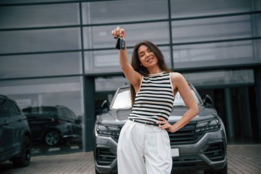 Yeni arabanın anahtarlarını. Mutlu sahip. Çekici genç bayan dışarıda, yepyeni arabasının yanında..