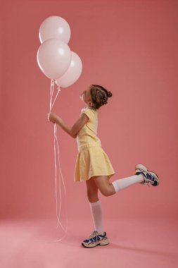Doğum günü partisi. Balonları tutuyorum. Şirin küçük kız pembe arka plana karşı..
