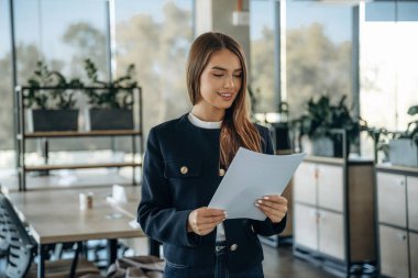 Belgeler ellerde, kağıtlar. Ofiste güzel bir kadın çalışıyor..