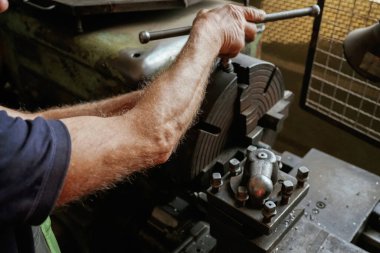 Meşgul adam. Atölyede endüstriyel makineleri çalıştıran işçilerin yakın çekimi.