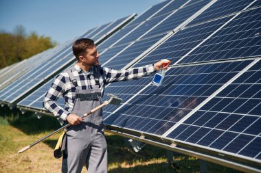 Yüzeyi temizleme prosedürü. Gündüz vakti fotovoltaik güneş panelleri olan bir mühendis..