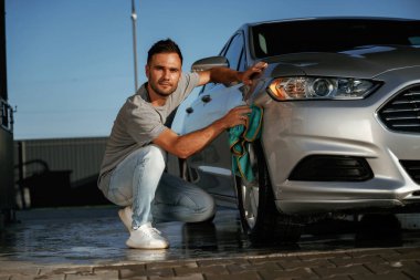 Araba yıkama, cilalama işi. Adam dışarıda otomobille geziyor..