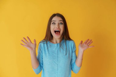 Şok ya da beklenti çığlıkları, el hareketi. Genç bayan sarı arka plana karşı..