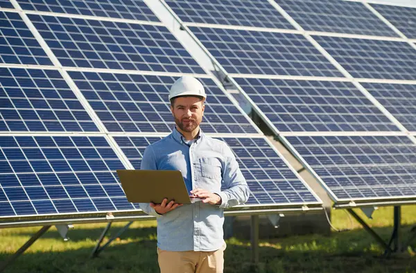Dizüstü bilgisayarla. Gündüz vakti fotovoltaik güneş panelleri olan bir mühendis..