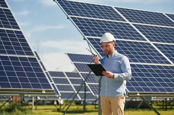 Telsiz kullanarak ve not defteri tutarak. Gündüz vakti fotovoltaik güneş panelleri olan bir mühendis..