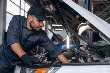 Yandan bak, kaputu aç. Araba tamirhanesinde çalışan bir tamirci..