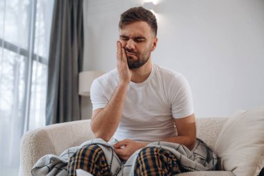 Diş ağrısı, oturma ve acı çekme. Hasta adam evde kendini kötü hissediyor..