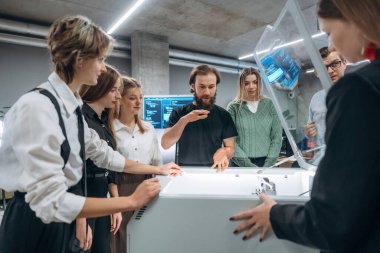 Cihazın nasıl çalıştığını açıklıyorum. Ofiste 3D yazıcının yanında insanlar var..