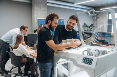 İletişim, bitmiş yazdırılmış nesne. Ofiste 3D yazıcının yanında insanlar var..