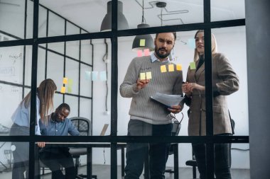 Camda bir sürü çıkartma var. Profesyonel işçiler modern ofiste birlikte çalışıyorlar..