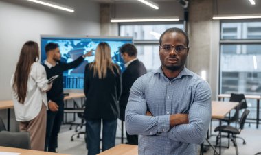 Afrikalı Amerikalı adam meslektaşlarına karşı duruyor. Bir grup ofis çalışanı içeride birlikte..