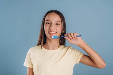 Diş fırçanı tutarak dişlerini temizle. Genç kız arka plana karşı..