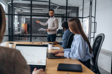 Kablosuz cihazlar, masadaki dizüstü bilgisayarlar. Profesyonel işçiler modern ofiste birlikte çalışıyorlar..