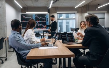 Büyük ekranda bilgi gösteriliyor. Bir grup ofis çalışanı içeride birlikte..