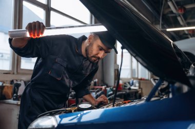 Kaputun altındaki yeri aydınlatıyordum. Araba tamirhanesinde çalışan bir tamirci..