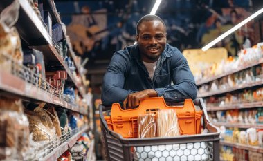 Gülümseyen, pozitif yüz ifadesi. Erkek müşteri süpermarkette..