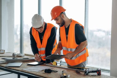 Projenin planı. İki inşaat işçisi bitmemiş odada birlikte..