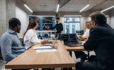 Büyük ekranda bilgi gösteriliyor. Bir grup ofis çalışanı içeride birlikte..