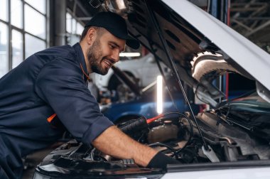 Gülümseyen, neşeli yüz ifadesi. Araba tamirhanesinde çalışan bir tamirci..