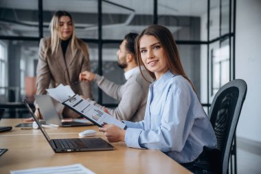 Evraklar ellerinde. Profesyonel işçiler modern ofiste birlikte çalışıyorlar..
