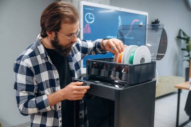 3D yazıcı için plastik yükleniyor. İnsan modern ofiste, tek kişidir..