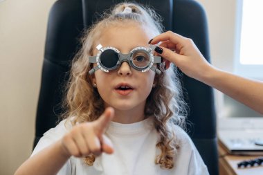 Portre, gözlüklü, ileriye bakıyor. Göz doktoru kliniğinde doktorla küçük bir kız..