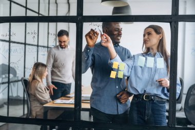 Fikirler camda, ayakta duruyor. Profesyonel işçiler modern ofiste birlikte çalışıyorlar..