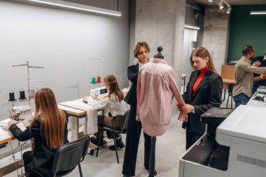 Moda konsepti. İnsanlar içeride dikiş makinelerinin yanında çalışıyor..