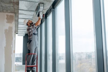 Pencerelerin yanında. Bir adam bitmemiş bir odayı yeniliyor..