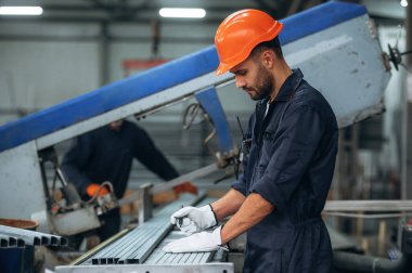 Makinenin yanında, operatör not alıyor. İnsanlar modern fabrikada çalışıyor..