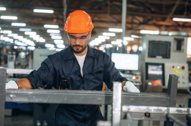 Metal parçalar, ayakta duruyor. İnsanlar modern fabrikada çalışıyor..