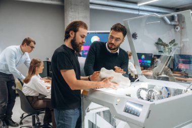 İletişim, bitmiş yazdırılmış nesne. Ofiste 3D yazıcının yanında insanlar var..
