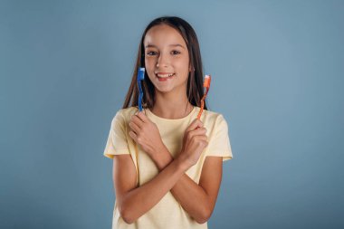 Kırmızı ve mavi diş fırçaları. Genç kız arka plana karşı..