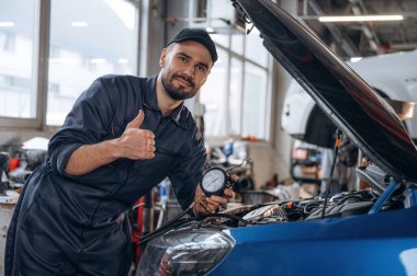 Şapkadayım, meşgulüm. Araba tamirhanesinde çalışan bir tamirci..