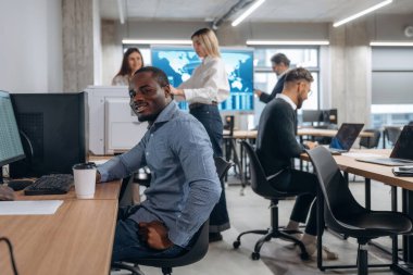 Pozitif siyah adam gülümsüyor. Bir grup ofis çalışanı içeride birlikte..