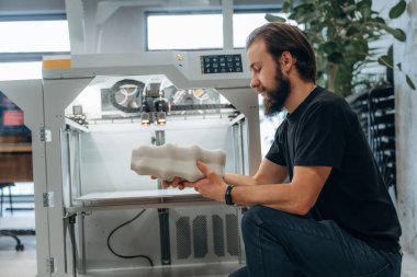 Ürün hazır. Adam 3D yazıcıyla ofiste..